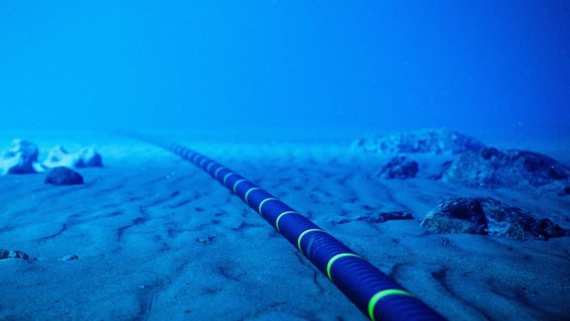 Remotely operated underwater vehicle inspecting a subsea communication cable on the ocean floor