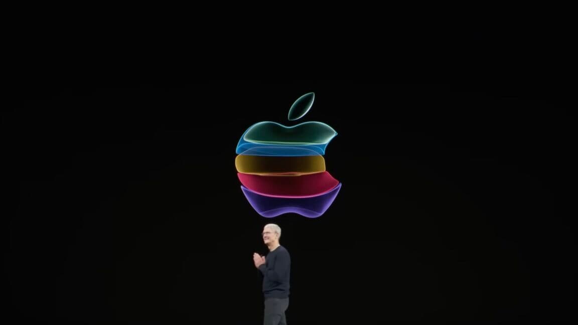 Tim Cook speaking on stage at an Apple event with a large screen behind him