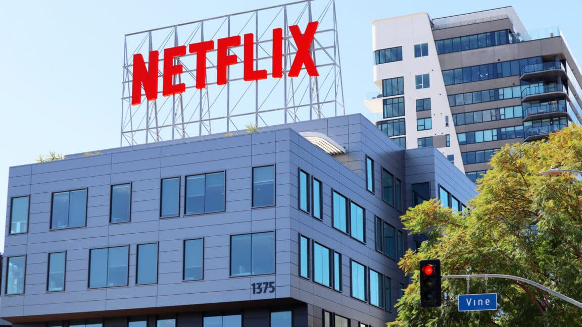 Netflix, Paramount and Warner Bros. Discovery logos over the Hollywood skyline at dusk