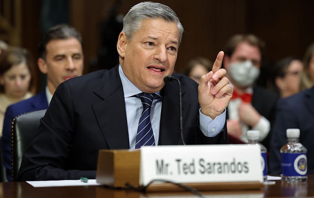 Ted Sarandos speaking in a parliamentary-style hearing room about the Netflix–HBO Max merger