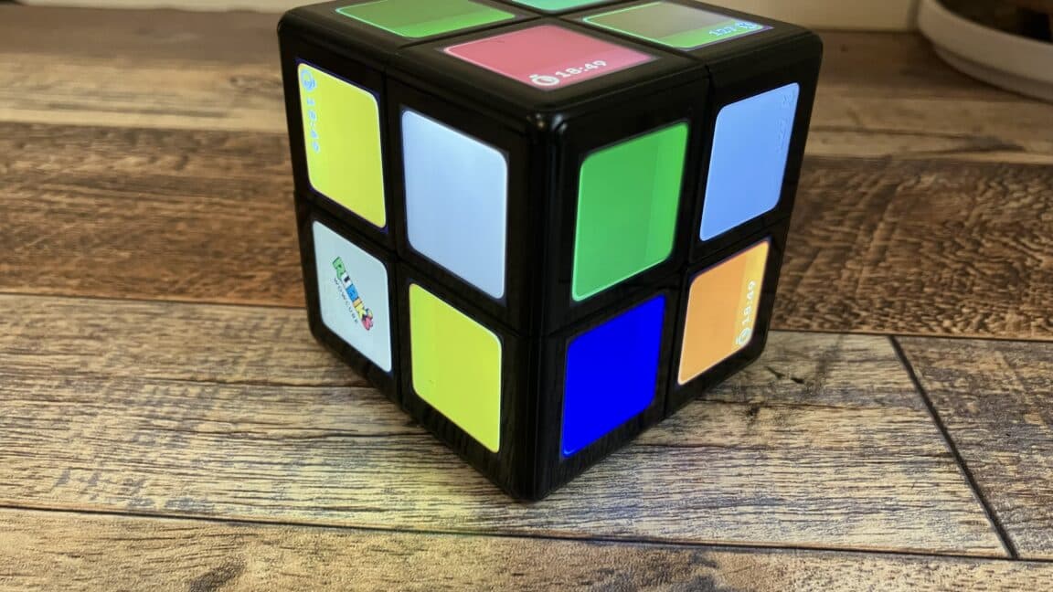 Electronic Rubik’s-style cube with animated screens on each face resting on a desk