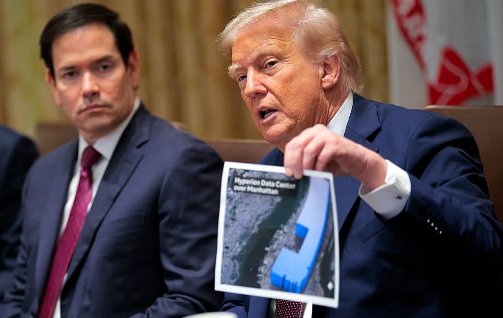 Donald Trump holding a picture of a large data center during a political event